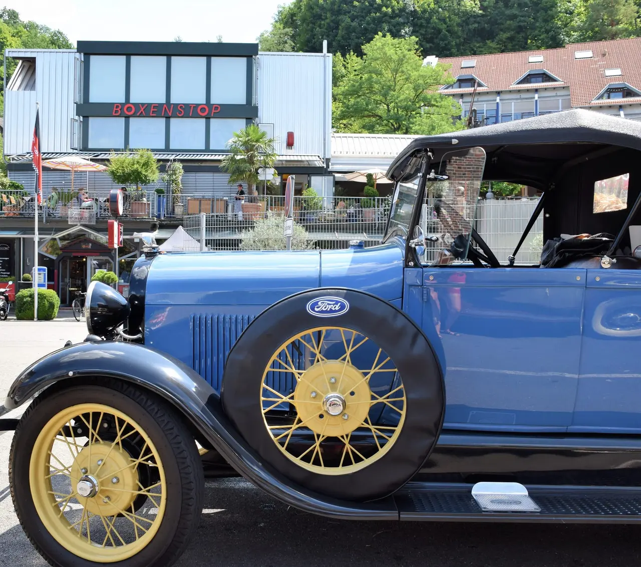 Blauer Ford Model A mit gelben Speichenrädern vor einem Hotel