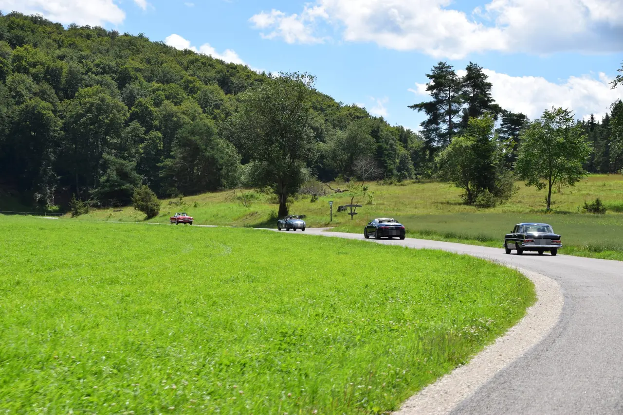 Oldtimer-Kolonne auf einer kurvigen Landstraße am Waldrand der Schwäbischen Alb